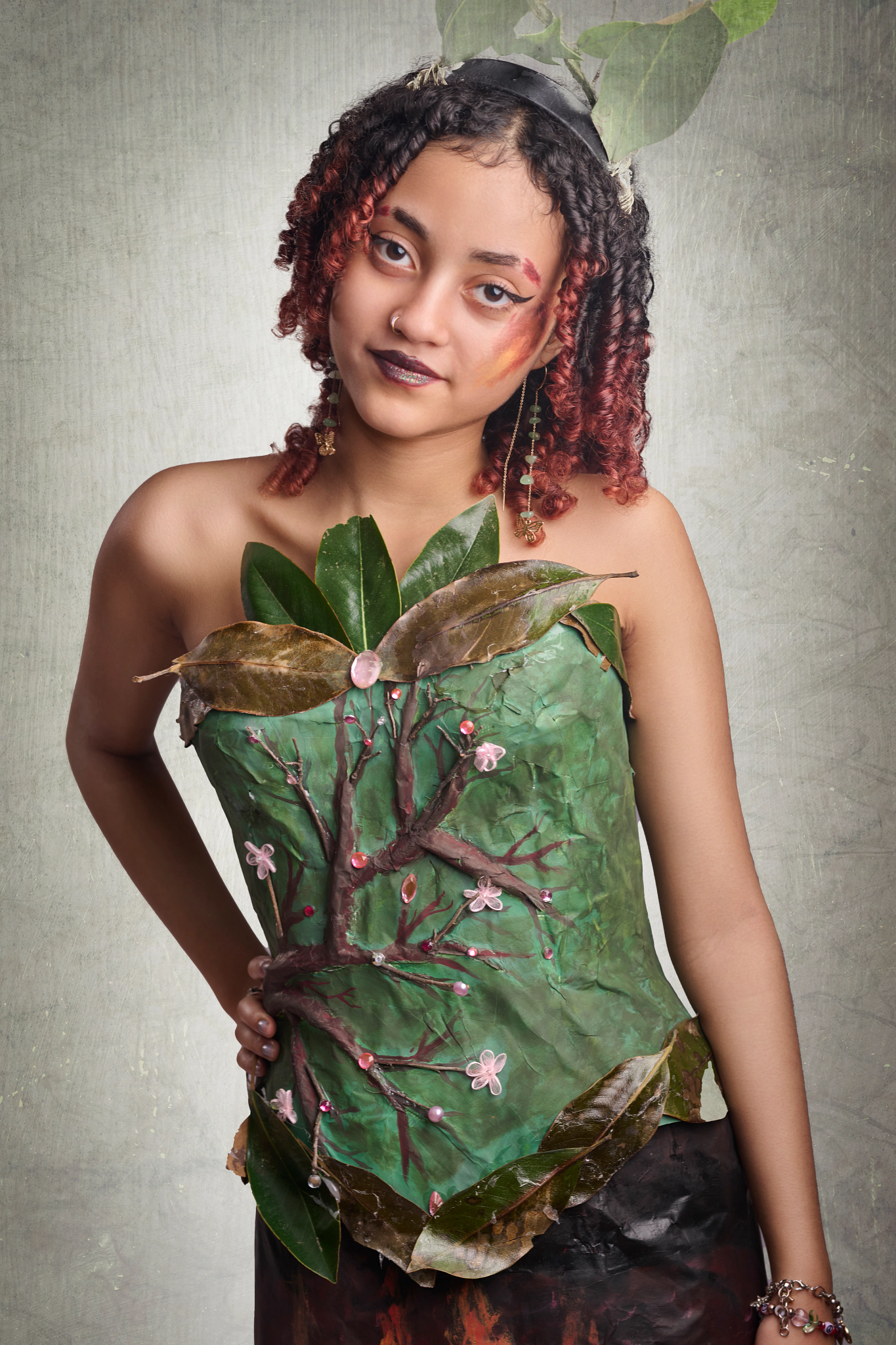 Recycle the Runway: Ember A high school student models an avant garde fashion made from recycled materials. The corset of the dress features a tree and leaves.