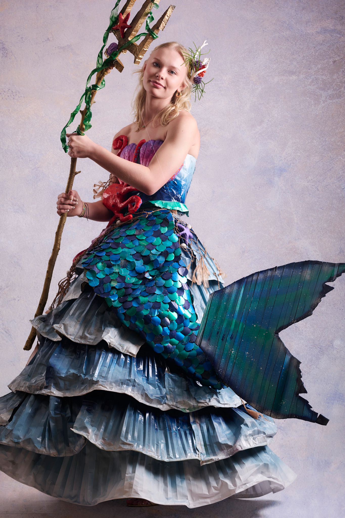 Recycle the Runway: Ocean Tempest A high school student models a mermaid - inspired gown and trident made from recycled materials.
