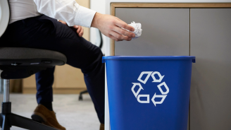 Man dropping screwed up paper into recycling bin, close up